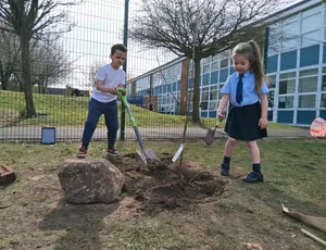Chidren taking part in Veolia Orchards planting event with a spade and an apple tree