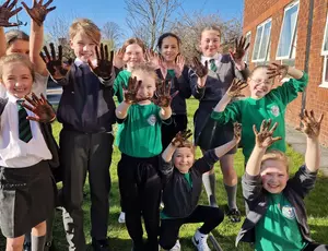 Children waving hands with Veolia staff at a orchard planting session